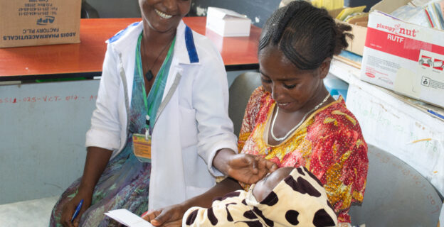 A health provider sits with a client and her newborn